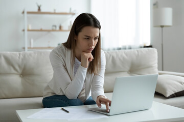 Frown young woman sit on couch feels tired exhausted after long usage of laptop looks at pc screen experiencing difficulties in bank application applying, search for right information having troubles