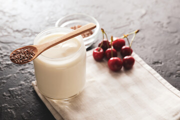Jar of yogurt with berry and flax seeds on dark background