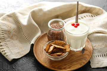Glass of yogurt and cookies with flax seeds on dark background