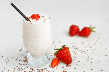 Glass of yogurt with strawberry and flax seeds on white background