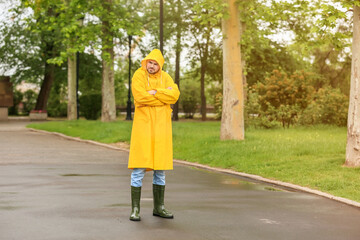 Displeased young man wearing raincoat outdoors
