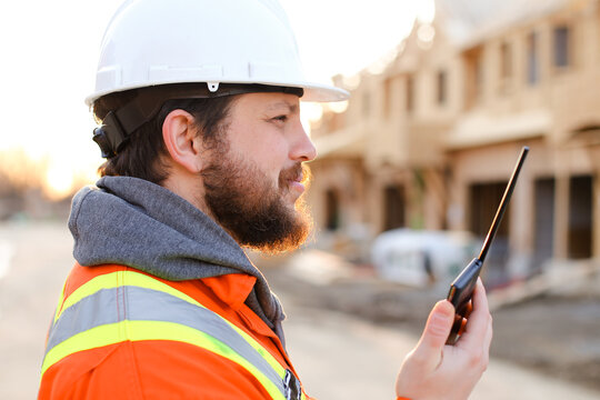 Portrait of european foreman talking by walkie talkie on construction site.