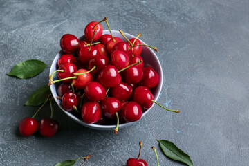 Bowl with sweet cherry on table