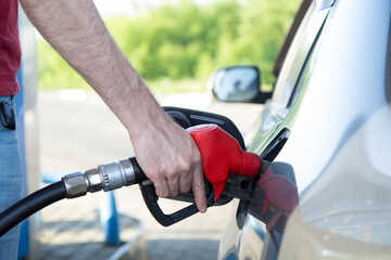 Refueling the car with gasoline. A man's hand holds a fluel gun and refuel his car.
