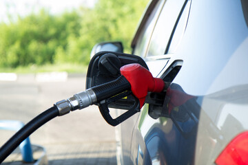 A fuel gun sticks out of the fuel hole of a car. Gas station.