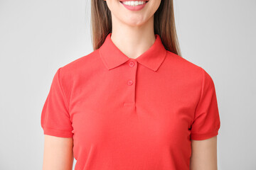 Beautiful young woman in stylish polo shirt on light background