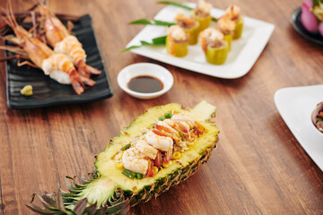 Table with with South Asian dishes like spiny lobsters, stuffed zuccini and fried rice served in pineapple bowl