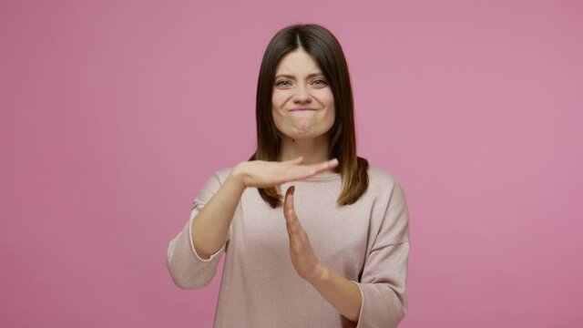 Need more time! Tired depressed brunette woman showing timeout gesture to camera and looking imploringly, asking for pause, break at work, declining suggestion. studio shot isolated on pink background