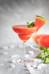 A frozen red drink garnished with watermelon and basil