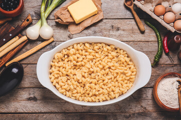 Baking dish with boiled pasta and ingredients on table