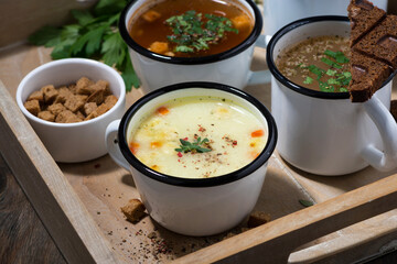 hot soups in mugs on wooden tray