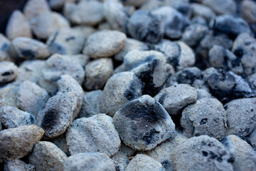 A closeup view of an barbecue area filled with used gray charcoal.