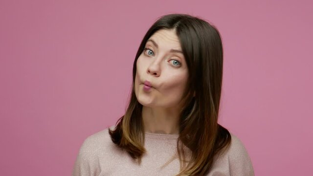 Closeup funny young woman showing fish face, duck grimace with pout lips, looking amazed stupid, making humorous dumb expression, sucking and choking. indoor studio shot isolated on pink background
