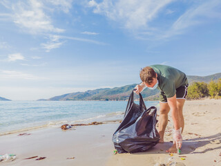 Man in gloves pick up plastic that pollute sea and forest. Problem of spilled rubbish trash garbage...