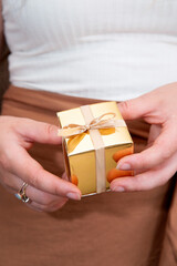 Women's hands holding gold gift box, Holiday present,birthday,Christmas, Father or Mother's, Valentine's day close-up