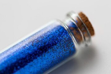 party, decoration and holidays concept - close up of ultramarine blue glitters in small glass...