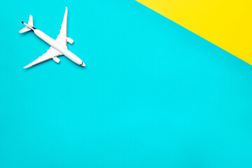 Travel background. White toy airplane, aircraft on bright blue and yellow backdrop. Flight or fly in sky air plane concept.