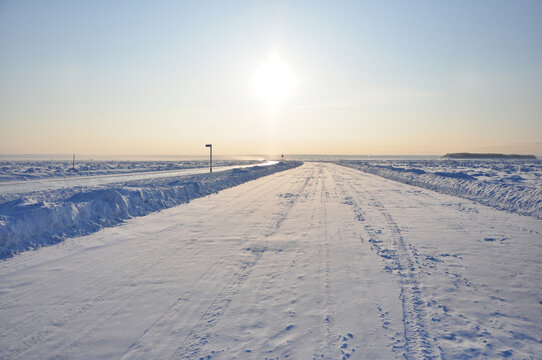 A long straight ice road on frozen Lena river, covered in snow during beautiful sunrise, Yakutsk, Russia