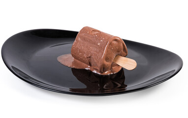 Slightly thawed chocolate ice cream on stick lies on dish