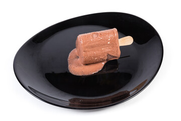 Slightly thawed chocolate ice cream on stick on black dish