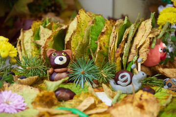 autumn composition with leaves and chestnuts,from chestnuts a bear and a snail from plasticine on autumn leaves for an autumn holiday © retbool