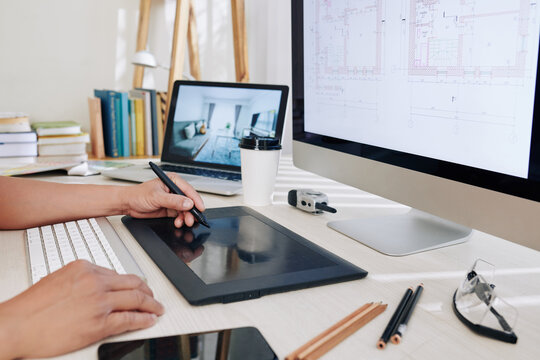 Cropped image of architect working at office desk and using graphic tablet when drawing house blueprint