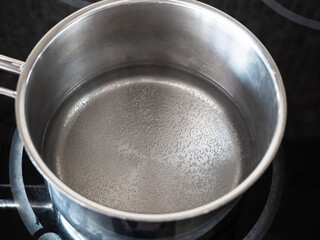 workshop for cleaning tarnished silver with aluminum foil and baking soda - water begins to boil in pot on kitchen electric stove