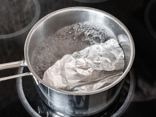 workshop for cleaning tarnished silver with aluminum foil and baking soda - boiling water solution of baking soda with aluminum foil and silver objects on electric stove