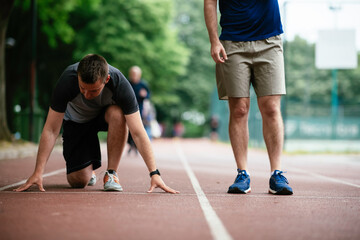 Young men exercising on a race track. Two young friends training outdoors.	