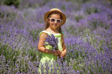 Portrait of a little girl in lavender . A child on a summer walk in a straw hat and sunglasses