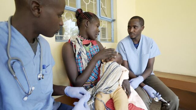Doctors working with mothers and babies in busy neonatal clinic. Africa