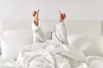 Foto op Aluminium gesture, comfort and morning concept - hands of young woman in hotel robe lying in bed and showing thumbs up at bedroom © Syda Productions