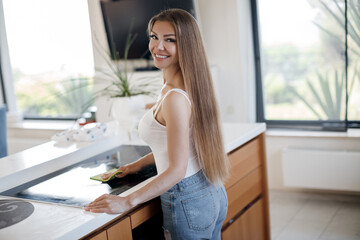Beautiful woman doing cleaning at home at kitchen