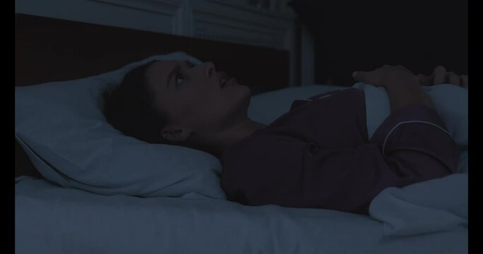 Awakened woman lying in bed having nightmare