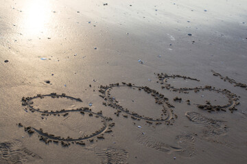 SOS big written on the beach by the sea.
