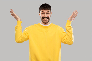 Fototapeta premium emotions and people concept - smiling young man in yellow sweatshirt over grey background