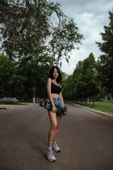 Young woman posing on street with skateboard in hands.