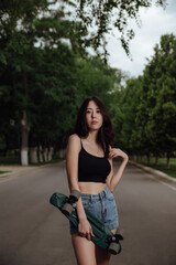 Fototapeta na wymiar Young woman posing on street with skateboard in hands.