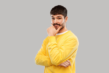 Fototapeta premium people concept - young man in yellow sweatshirt thinking over grey background