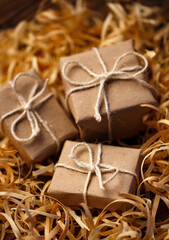 Rustic little gift boxes lie in natural wood shavings.