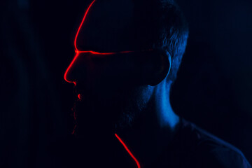 Man in dark with face cross illuminated by red laser on contour. Face scanning