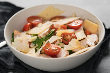 Fresh caesar salad with chicken and cherry tomatoes in white bowl