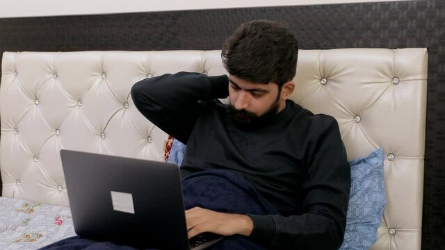 Young Male Doing Work From Home Due To The Outbreak Of Coronavirus In India. A Stressed Indian Man Massaging His Neck With His Hand While Working On His Laptop During Covid-19 Pandemic Time