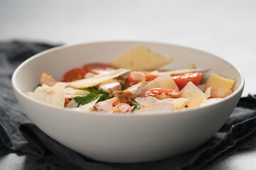 Fresh caesar salad with chicken and cherry tomatoes in white bowl