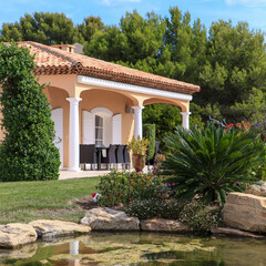 Mediterranean house with palm trees and flowers over a pond
