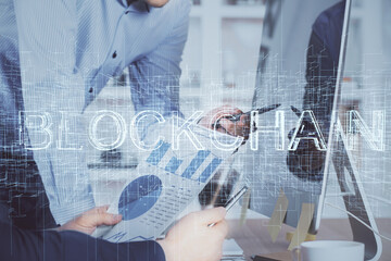Crypto currency theme hologram with businessman working on computer on background. Concept of blockchain. Multi exposure.