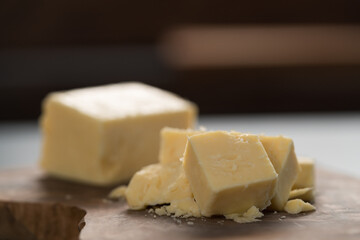 White cheddar cheese pieces on olive wood board