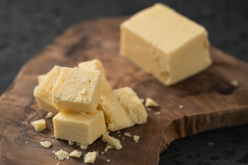 White cheddar cheese pieces on olive wood board