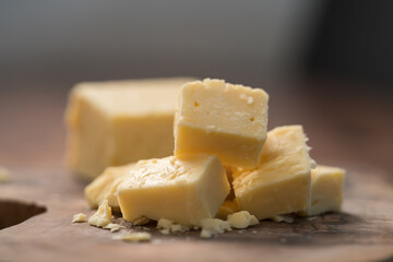 White cheddar cheese pieces on olive wood board