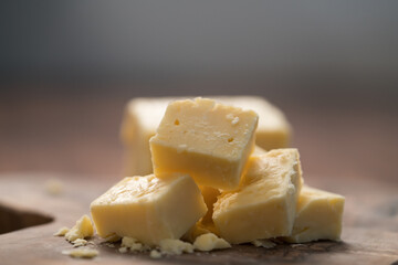 White cheddar cheese pieces on olive wood board